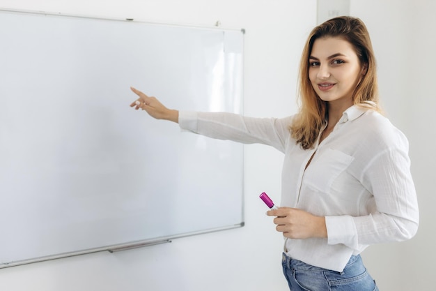 Professora jovem aponta um dedo para um quadro branco Um lugar para o seu texto