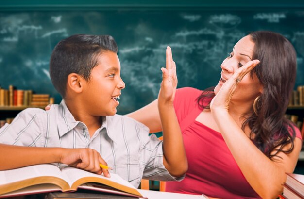 Professora latina a dar um "high fist" a um rapaz hispânico na sala de aula.