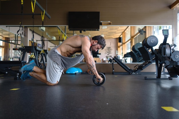 Profil eines Mannes, der mit einer Rolle im Fitnessstudio Bauchmuskeln macht