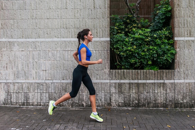 Profilansicht einer sportlichen jungen Frau, die im Freien trainiert Fitness-Mädchen, das auf dem Bürgersteig läuft