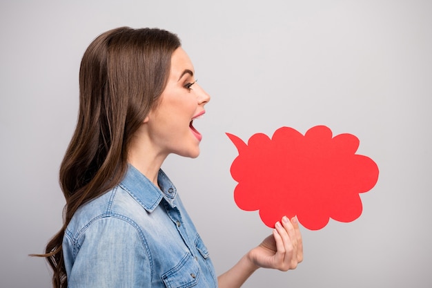 Foto profilfoto der hübschen lustigen dame halten leere papierwolkenhand nahe offenem mund, der neuheitsinformationsmenge-leute tragen lässiges jeans-jeanshemd isolierte graue farbe tragen