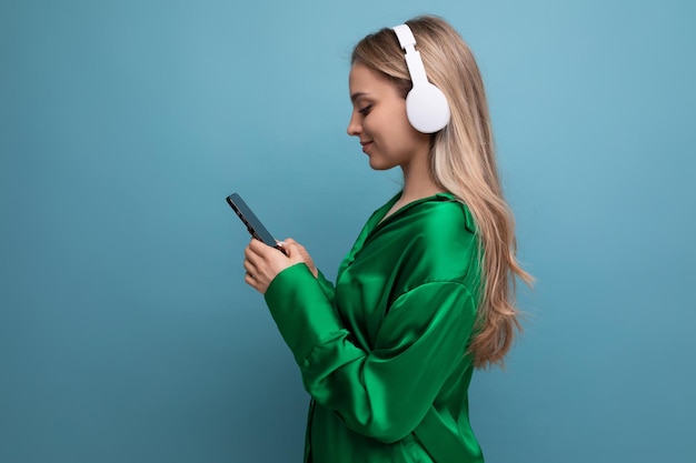 Profilfoto einer süßen blonden jungen erwachsenen Frau, die Musik mit Kopfhörern auf blauem Hintergrund hört