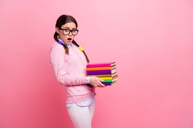 Profilfoto einer ziemlich schockierten Studentendame, die schwere Bücherstapel hält, bereiten die Prüfung vor College-Universität große Hausaufgabenbibliothek müde tragen Hemd Pullover Spezifikationen isoliert rosa Farbhintergrund