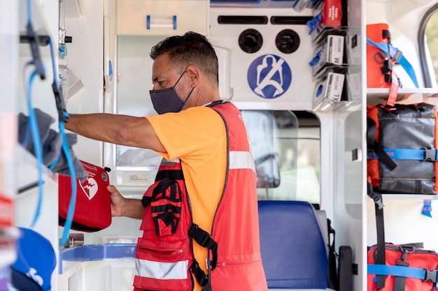 Profilfoto eines Arztes mit Gesichtsmaske, der Geräte in einem Krankenwagen benutzt