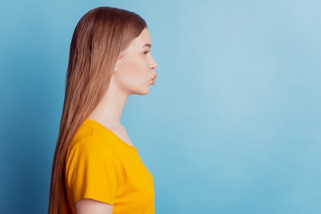 Profilporträt der romantischen Freundin sieht leer aus, sendet Luftkuss auf blauem Hintergrund