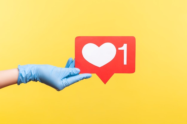 Profilseitenansicht Nahaufnahme der menschlichen Hand in blauen chirurgischen Handschuhen, die soziale Medien wie einen Stock halten.