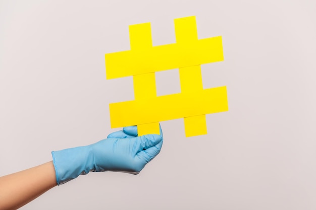 Profilseitenansicht Nahaufnahme der menschlichen Hand in blauen OP-Handschuhen mit gelbem Hashtag.