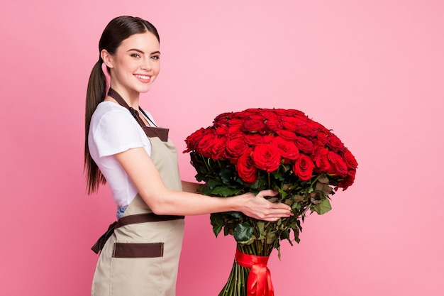 Profilseitenansicht-Porträt eines fröhlichen Mädchens, das große rote Rosen hält