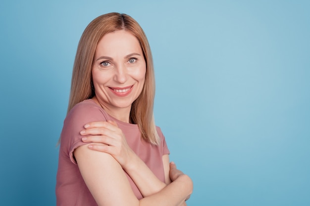 Profilseitenfoto einer jungen attraktiven Frau, die glückliches positives Lächeln umarmt, kuschelt sich isoliert über blauem Hintergrund