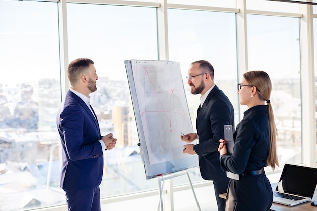 Profissionais de negócios. Um grupo de jovens empresários de sucesso está analisando dados usando gráficos enquanto passam o tempo em um novo escritório moderno.