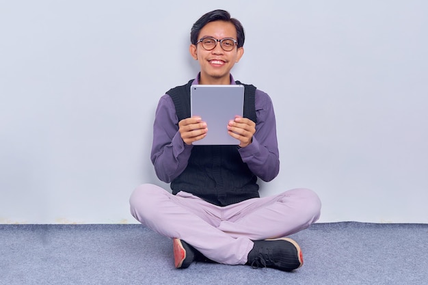Profissional alegre em óculos estudando relatório Jovem asiático vestindo camisa usando tablet Conceito de tecnologia digital