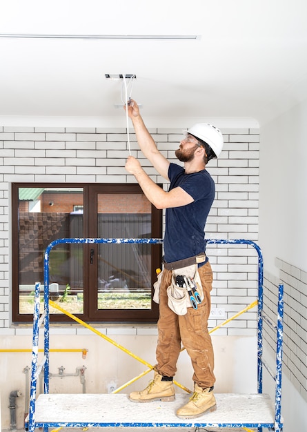 Profissional de macacão com ferramentas no fundo do canteiro de obras de corpo inteiro.