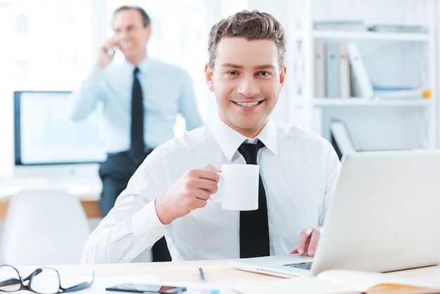 profissional de negócios. empresário alegre em trajes formais segurando uma xícara de café