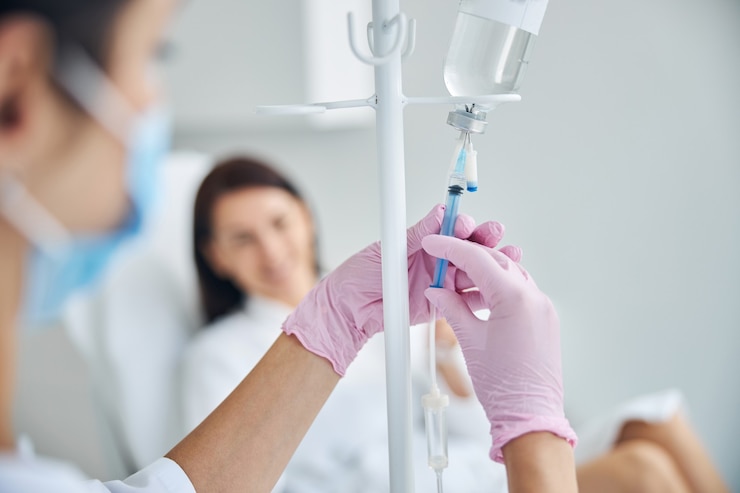 Foto profissional experiente em cuidados de saúde caucasianos preparando uma paciente de cabelos escuros para a terapia com vitaminas intravenosas