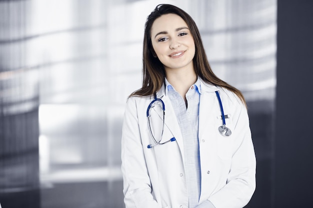 Profissional jovem médica está olhando para a câmera com um sorriso. Terapeuta no trabalho no escritório de uma clínica. Conceito de medicina.