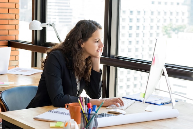 Foto profissional linda jovem empresária, concentrando-se em usar o computador