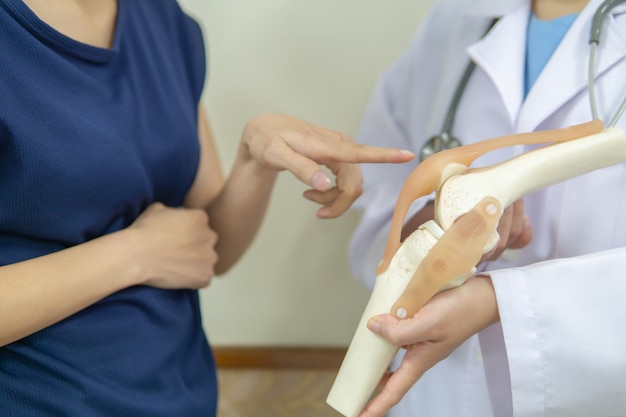 Foto profissional médico está dando um paciente do sexo feminino um local com uma dor no joelho.