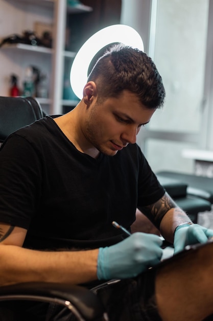 Profissional mestre de tatuagem criativa com caneta desenha esboço em papel em estúdio. Fluxo de trabalho do artista