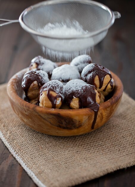 Profiterole en placa de madera sobre fondo oscuro