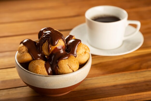 Profiteroles deliciosos con café en la mesa