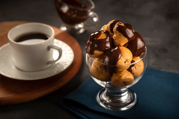 Profiteroles deliciosos con café en la mesa