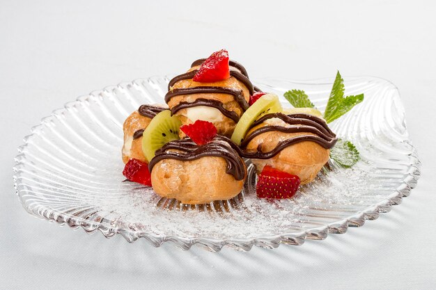 Profiteroles doces com creme e fatias de morango e kiwi