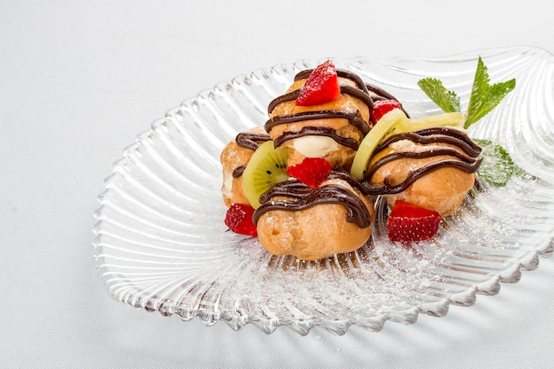 Profiteroles dulces con natillas y rodajas de fresa y kiwi