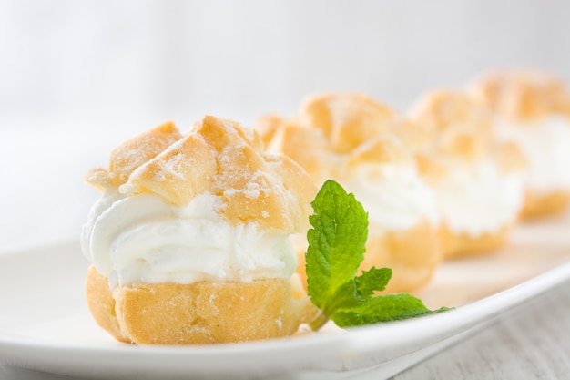 Profiteroles frescos com creme e na mesa de madeira branca