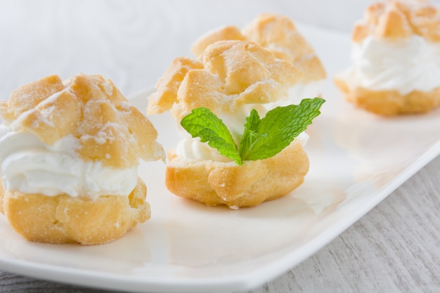 Profiteroles frescos com creme na mesa de madeira branca