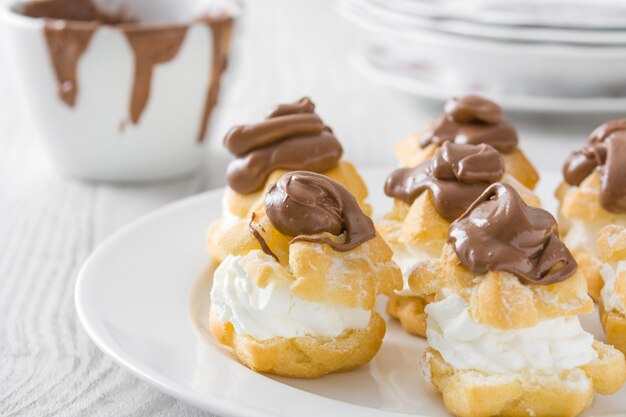 Profiteroles frescos con crema y mesa de madera blanca