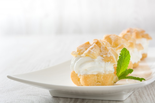 Profiteroles frescos con crema en la mesa de madera blanca