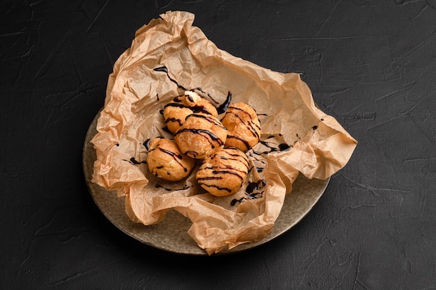 Profiteroles profiteroles com chocolate e cobertura de fundo preto