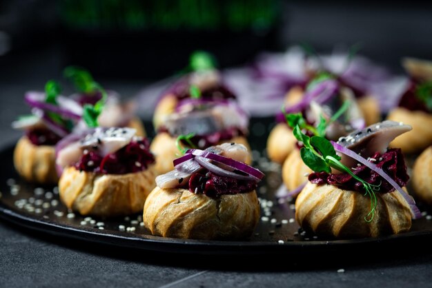 Profiteroles con queso cottage de arenque y cebolla roja sobre un fondo oscuro