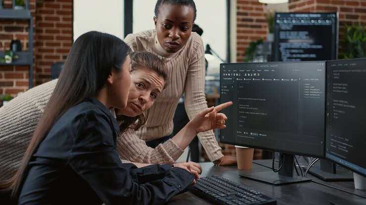 Foto programador apuntando a la pantalla de la computadora explicando el código en ejecución a los compañeros de trabajo intercambiando ideas de software en una agencia independiente. equipo mixto de ingenieros de software colaborando en el proyecto del grupo ti.