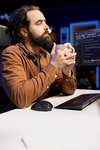 Foto programador bebiendo café y escribiendo líneas de código filtrando tráfico malicioso