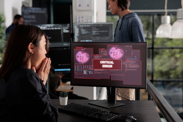 Programador conmocionado escribiendo código html que encuentra una alerta de piratería en la computadora, lidiando con un error inesperado del sistema y un mensaje parpadeando en el monitor. Oficina de desarrollo de ciberseguridad.