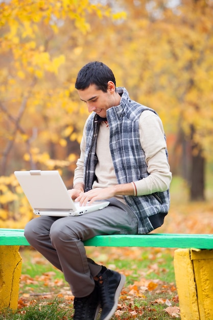 Programador con cuaderno sentado en el parque de otoño