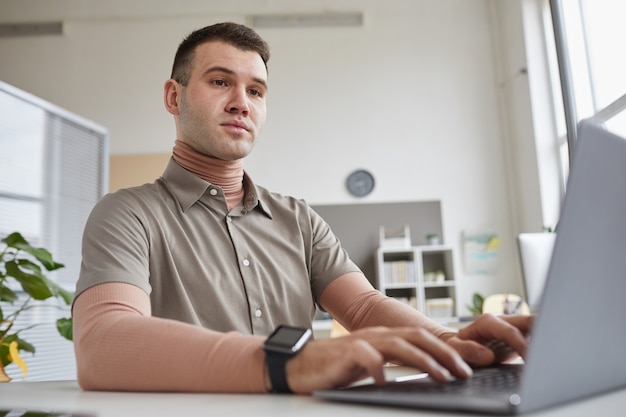 Programador de computador sentado à mesa e digitando no laptop do escritório