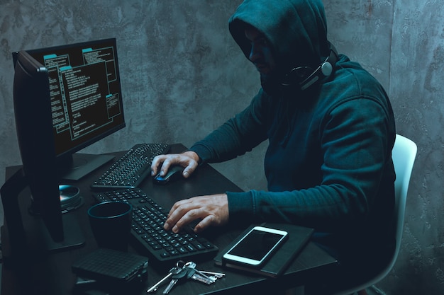 Programador de hacker usando computador em quarto escuro