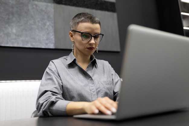 Programador de mulher masculina com corte de cabelo curto trabalhando em laptop em escritório forte