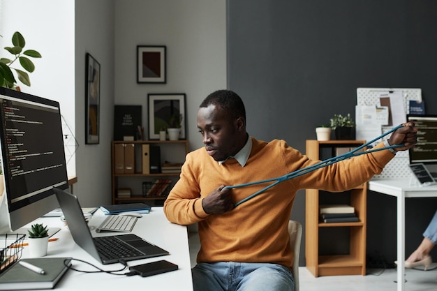 Programador de TI treinando com elástico durante seu trabalho