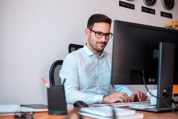 Foto programador encantado con gafas utilizando una computadora.