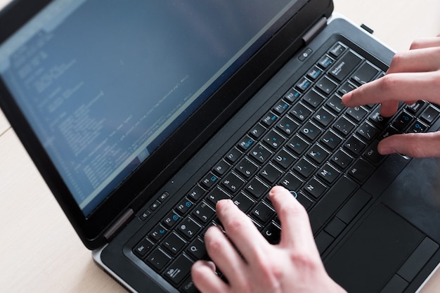 Programador escribiendo código en el teclado del portátil