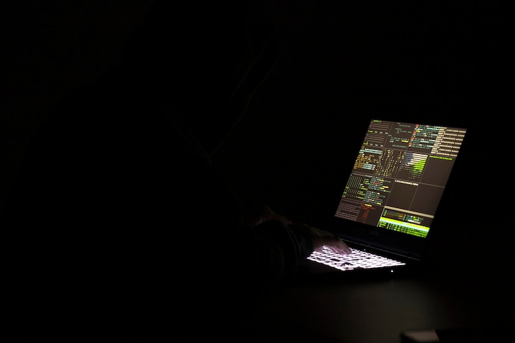 Foto un programador informático y un hacker imprimen un código en el teclado de una computadora portátil para entrar en un misterioso sistema organizativo