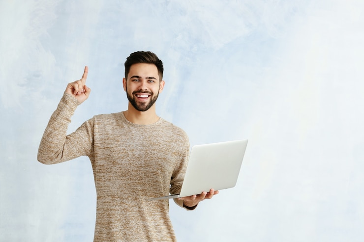 Foto programador masculino com laptop e dedo indicador levantado na cor