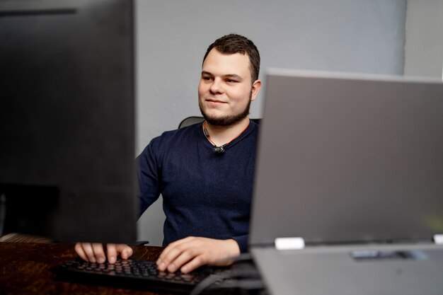 Foto programador masculino que trabaja en la computadora de escritorio cerca del monitor en la oficina en la empresa de desarrollo de software.