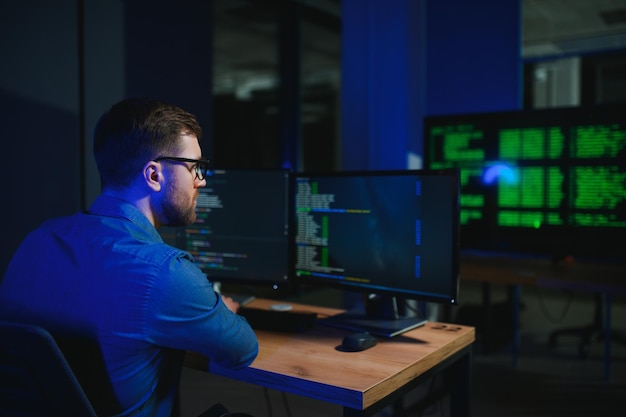 Programador masculino trabalhando em um computador de mesa em uma mesa branca no escritório