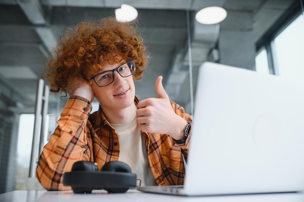 El programador masculino usa anteojos para protegerse los ojos mientras trabaja de manera independiente a través de una computadora portátil. Un estudiante inteligente ve un tutorial en una netbook.