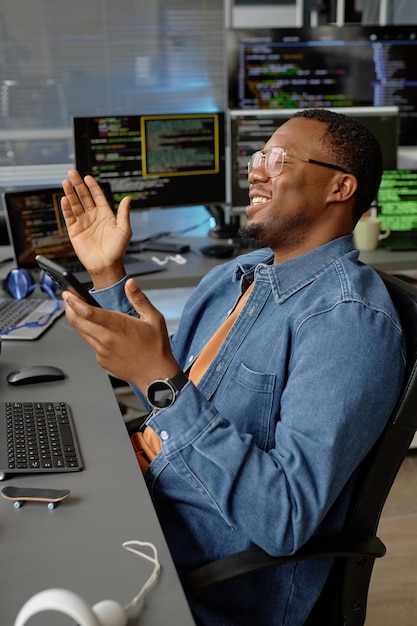 Un programador negro sonriente aplaudiendo alegremente