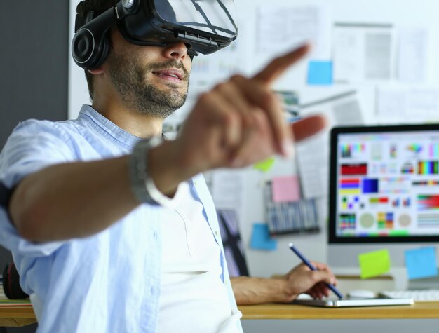 Programador de software masculino joven que prueba una nueva aplicación con gafas de realidad virtual 3d en la oficina